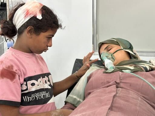 A little girl comforts her mother after they were wounded in a strike north of Nuseirat camp in Gaza.